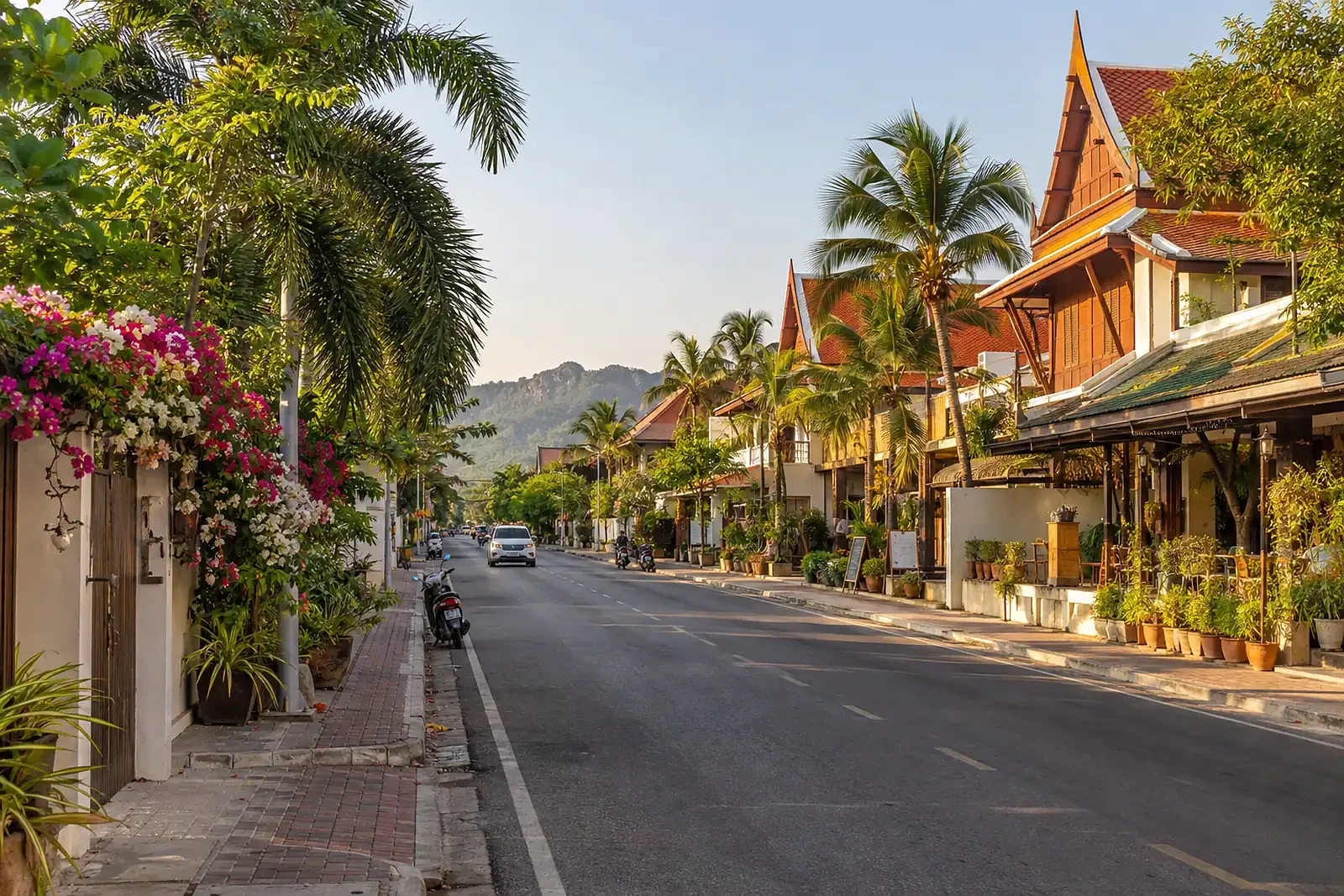 Straße in Hua Hin mit niedrigen Gebäuden und tropischen Bäumen